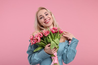 Happy young woman with beautiful bouquet on dusty pink background