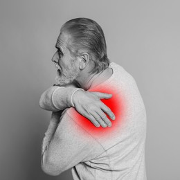 Senior man suffering from rheumatism on light background. Black and white effect with red accent in painful area