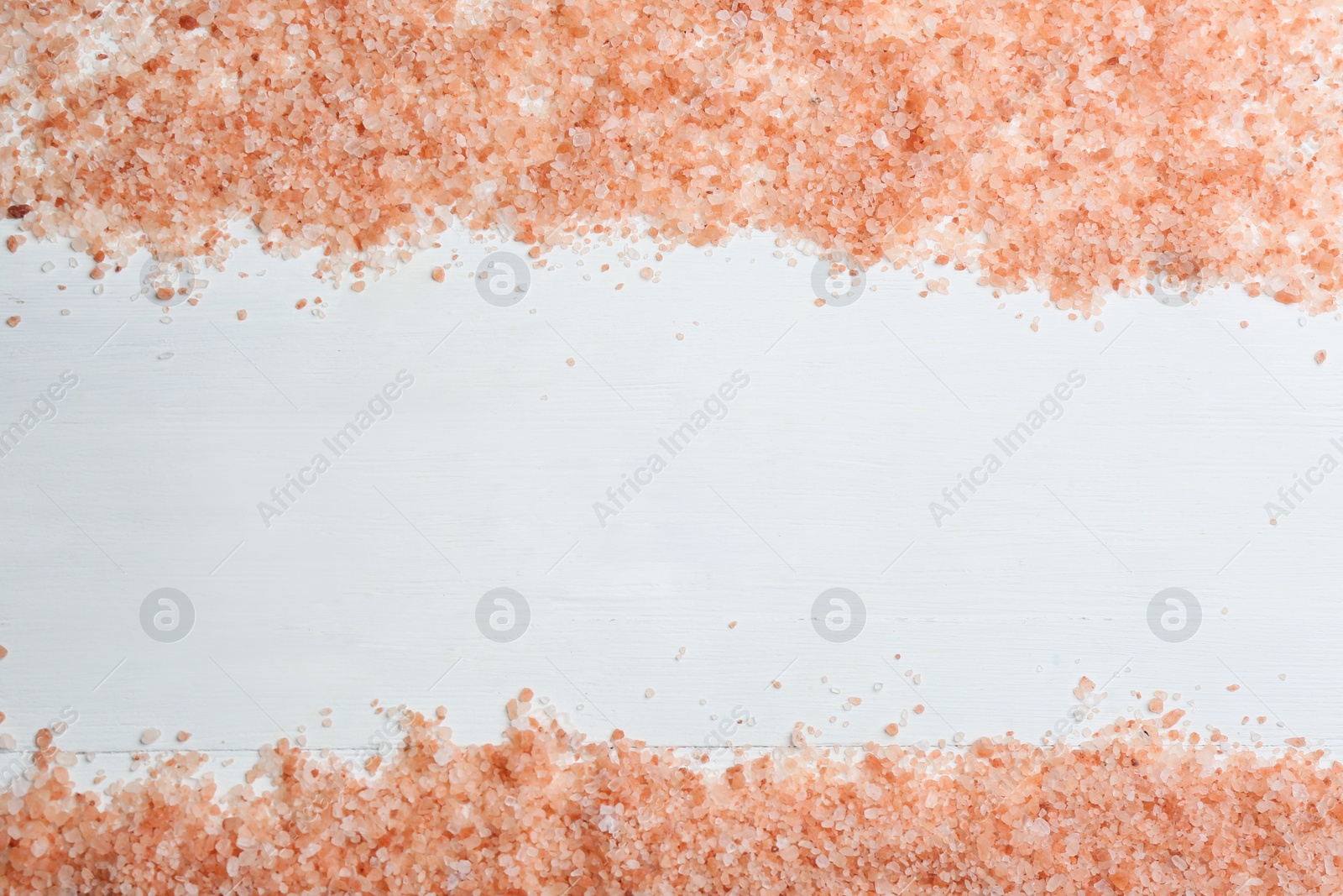 Photo of Pink himalayan salt on white wooden table, flat lay. Space for text