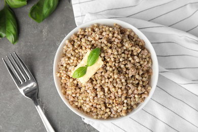 Photo of Tasty buckwheat porridge with butter on grey table, flat lay