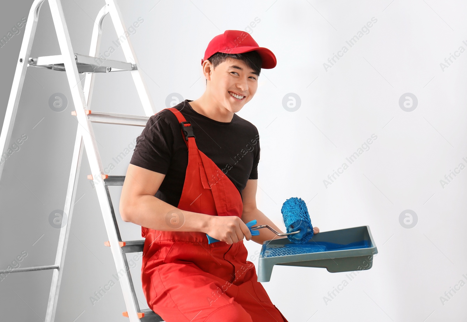 Photo of Male decorator with paint and roller indoors