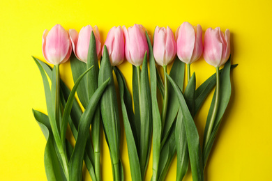 Photo of Beautiful pink spring tulips on yellow background, flat lay