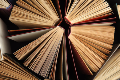 Photo of Many different hardcover books on dark background, top view