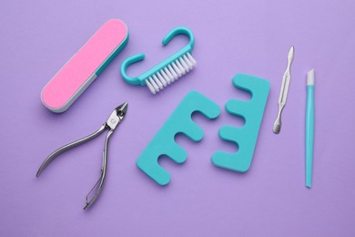 Set of pedicure tools on violet background, flat lay