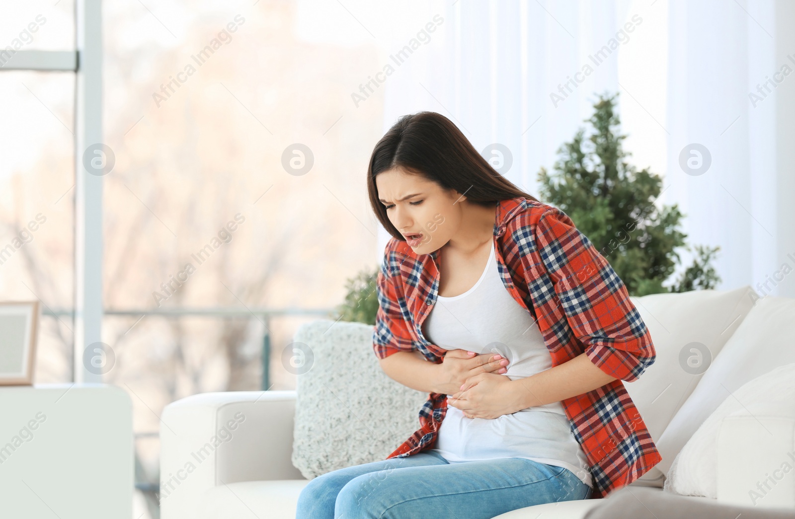 Photo of Young woman suffering from stomach ache at home