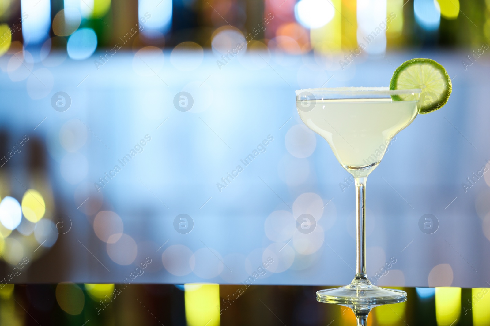 Photo of Glass of fresh alcoholic cocktail on bar counter. Space for text