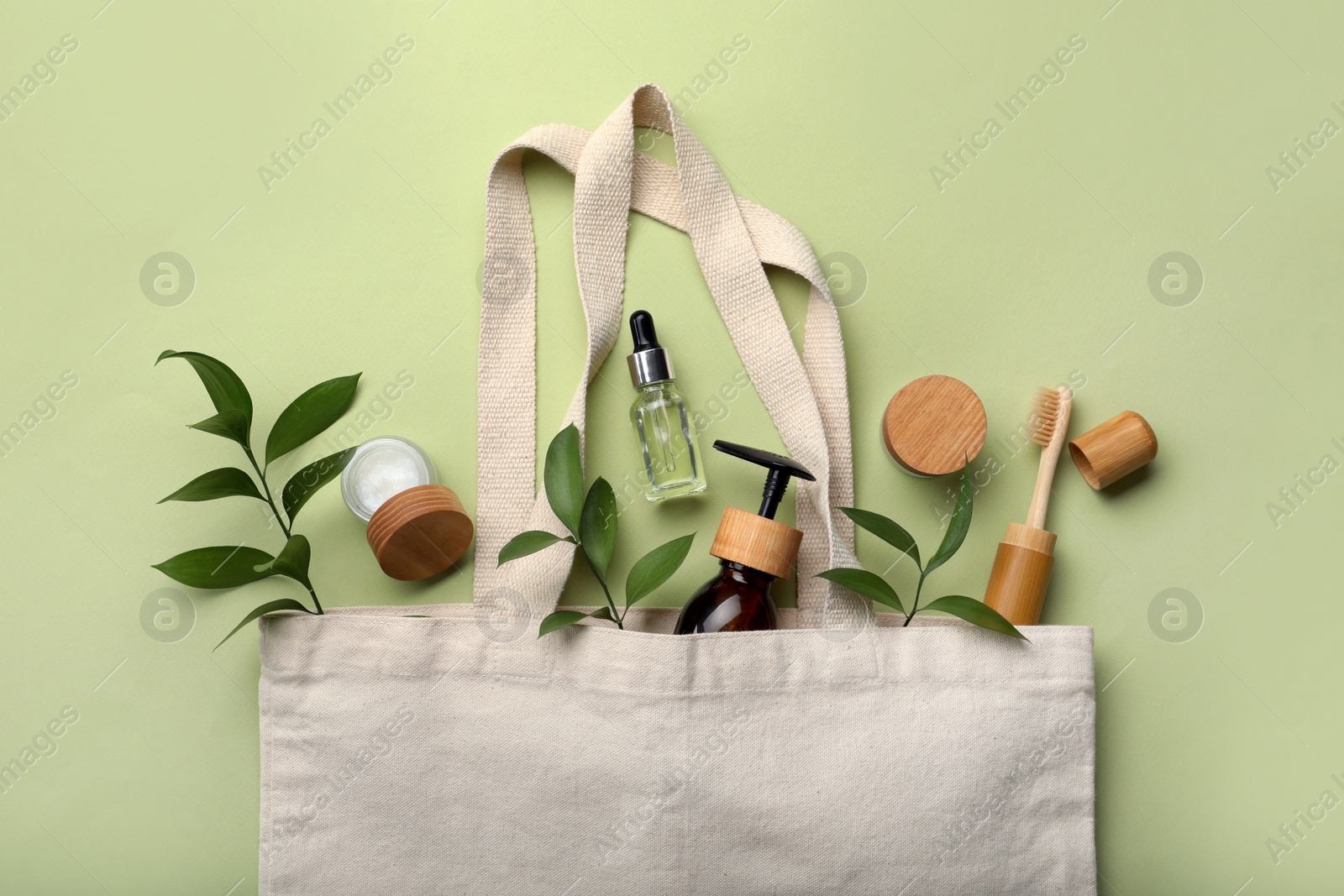 Photo of Bag with eco friendly products on green background, flat lay