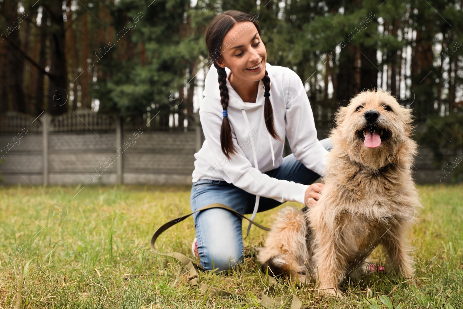 Photo of Female volunteer with homeless dog at animal shelter outdoors