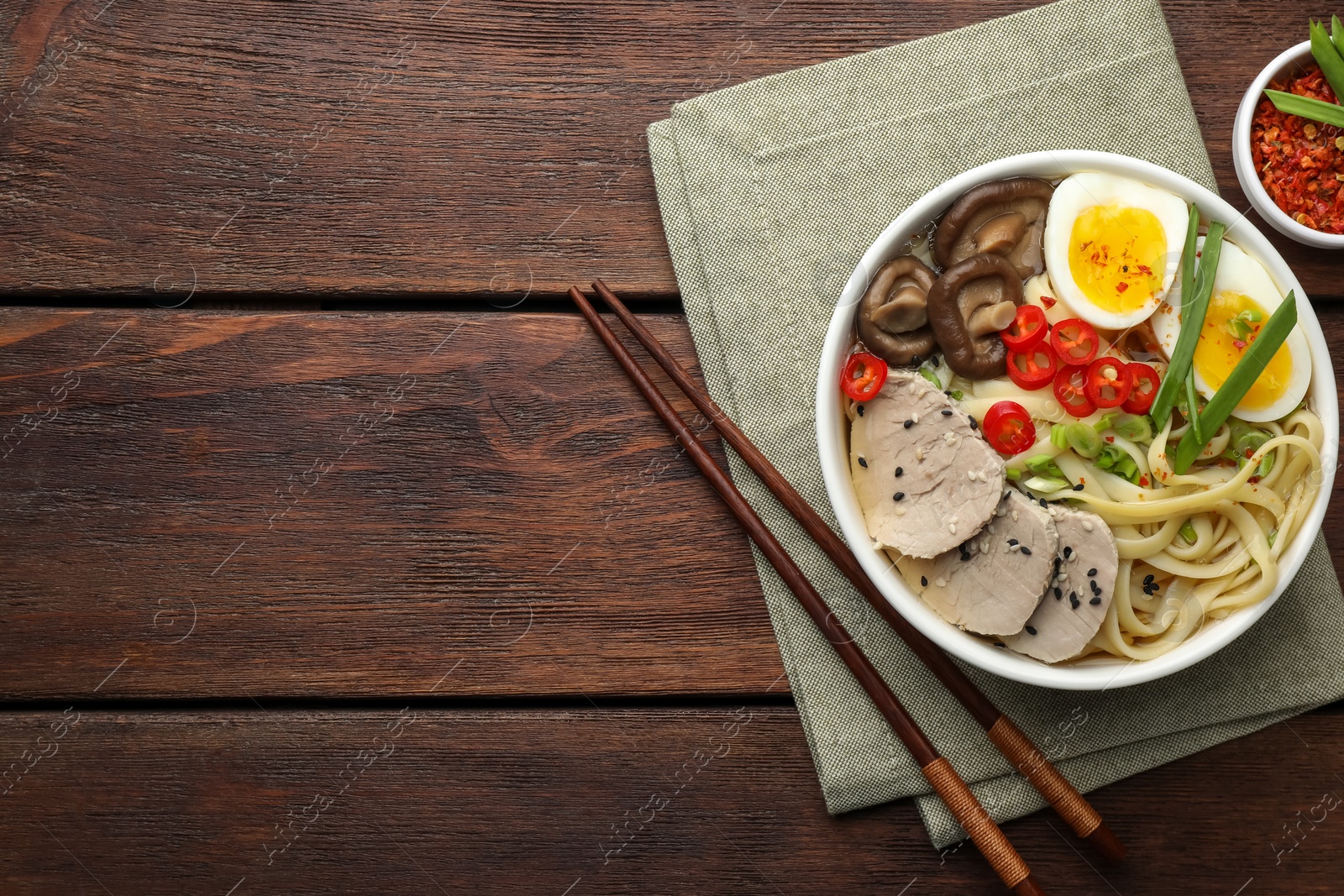 Photo of Delicious ramen with meat in bowl served on wooden table, flat lay. Space for text. Noodle soup