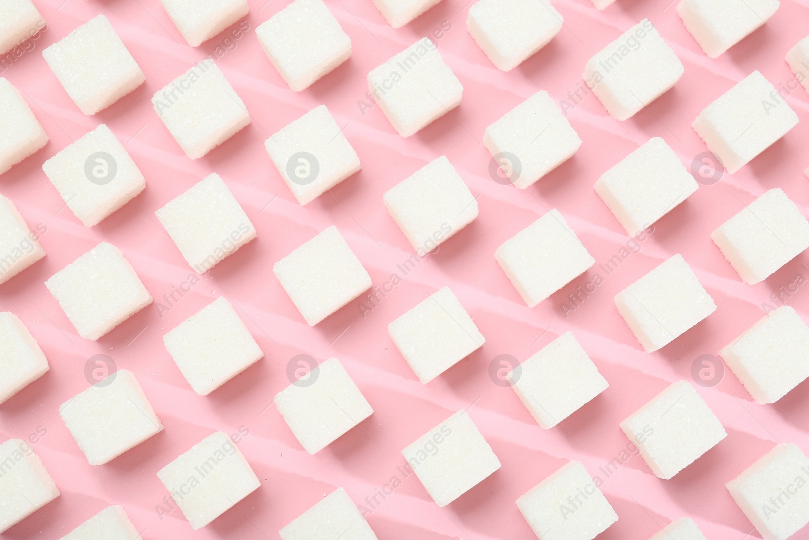 Photo of White sugar cubes on pink background, top view