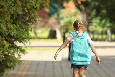 Photo of Little girl with backpack going to school, back view. Space for text
