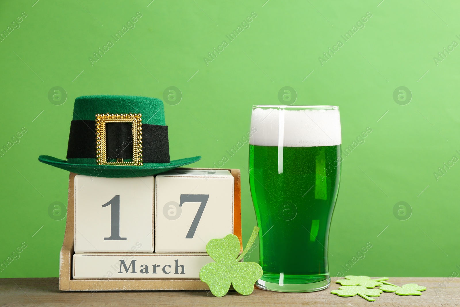 Photo of Composition with green beer and clover leaves on wooden table. St. Patrick's Day celebration