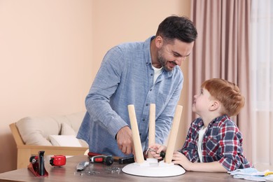 Photo of Father teaching son how to make stool at home. Repair work