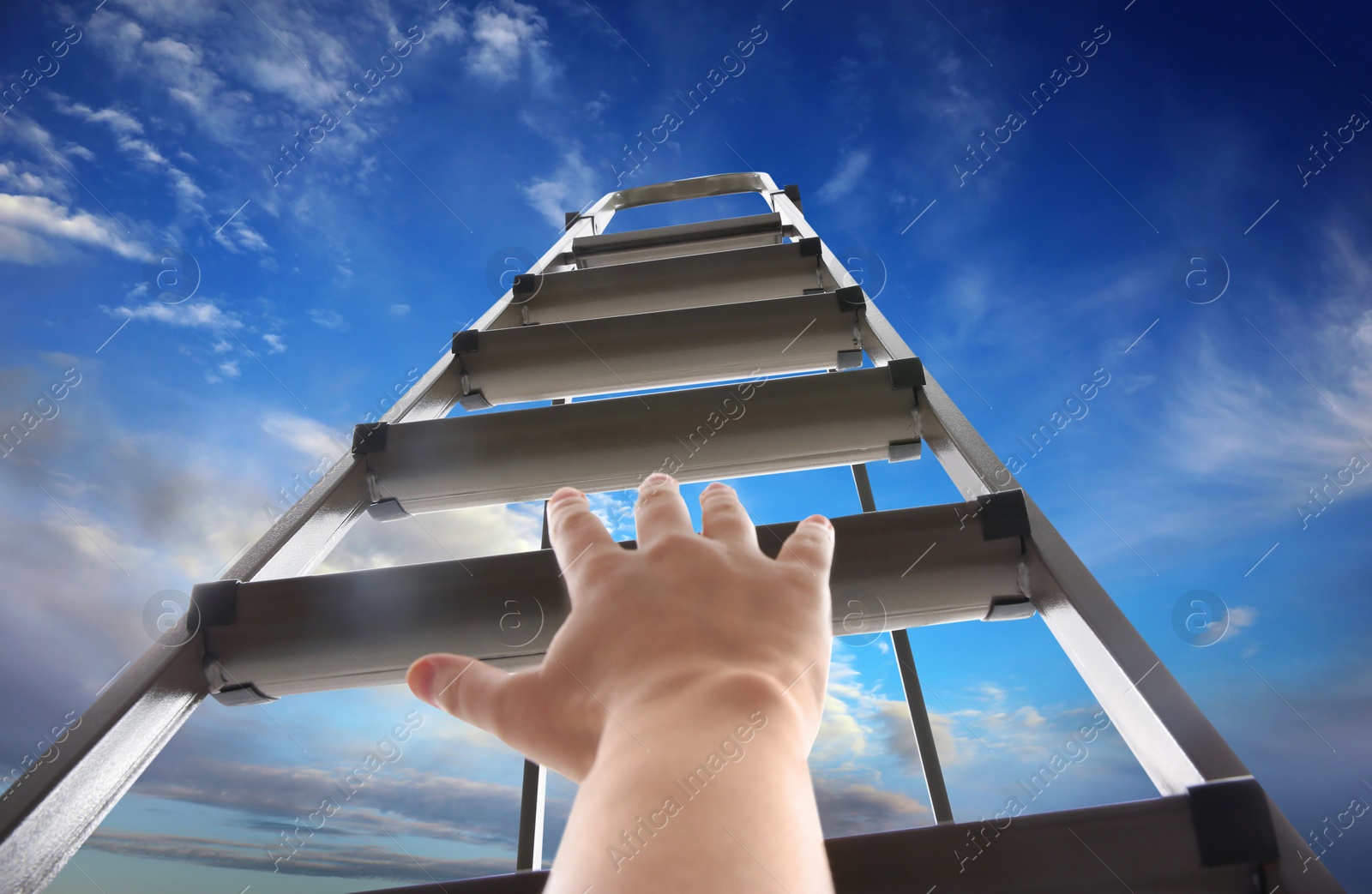 Image of Woman climbing up stepladder against blue sky with clouds, closeup