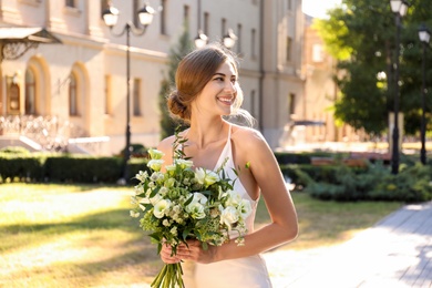 Gorgeous bride in beautiful wedding dress with bouquet outdoors