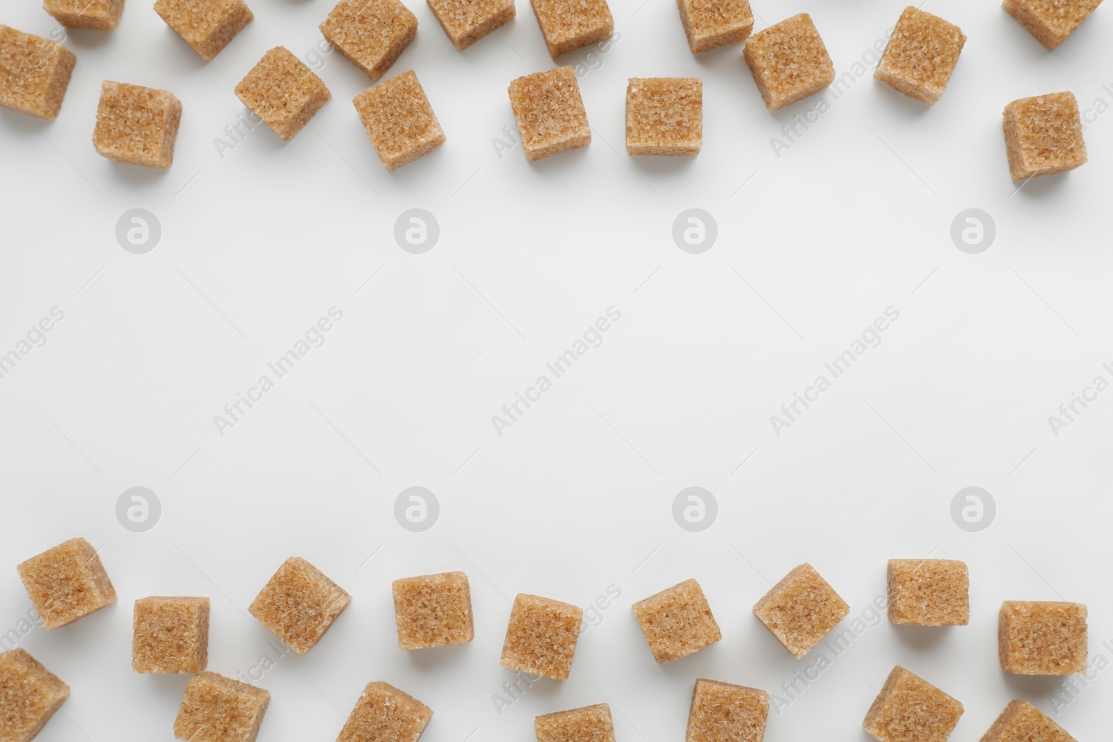 Photo of Brown sugar cubes on white background, top view. Space for text