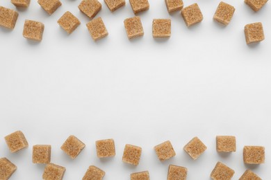 Brown sugar cubes on white background, top view. Space for text