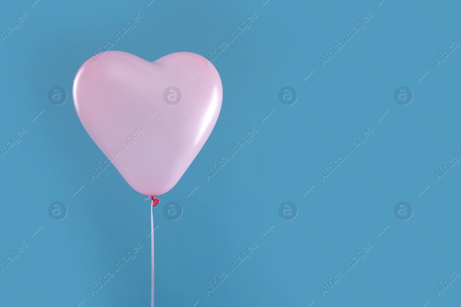 Photo of Festive heart shaped balloon on light blue background. Space for text