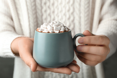 Photo of Woman holding cup of aromatic cocoa with marshmallows, closeup