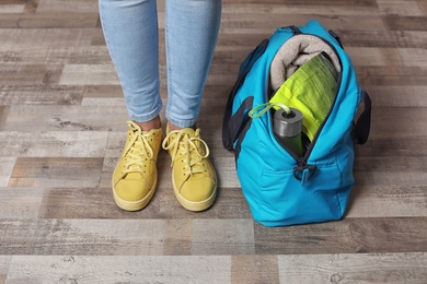 Photo of Young woman in sportswear and bag with gym equipment indoors