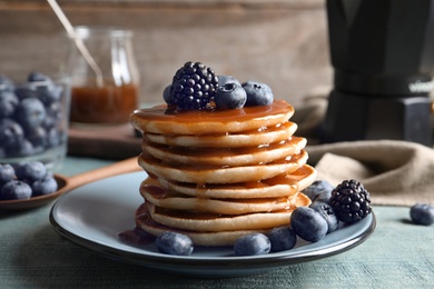 Tasty pancakes with berries and syrup on plate