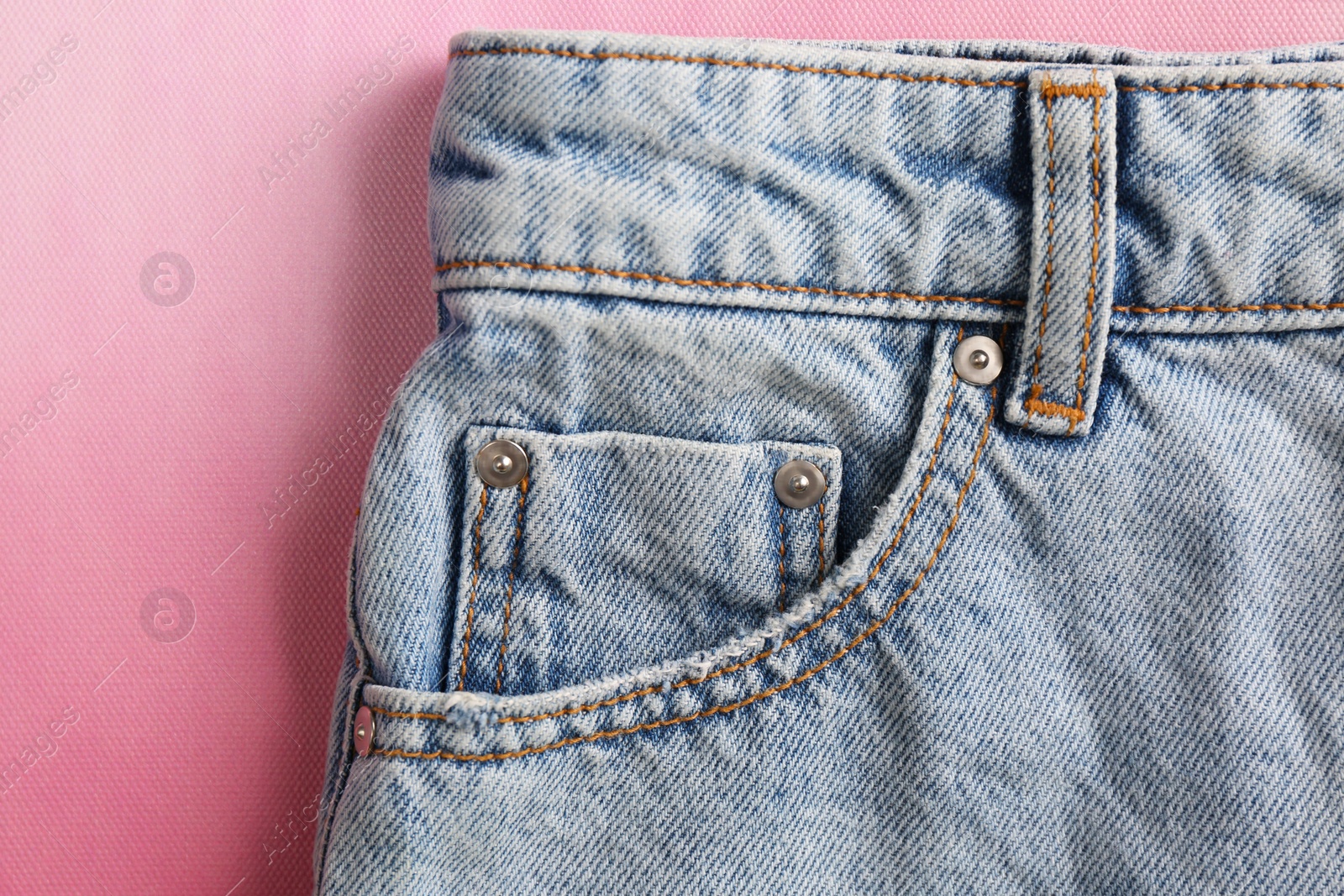 Photo of Stylish light blue jeans on pink background, closeup of inset pocket