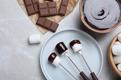 Photo of Tasty marshmallows dipped into chocolate on light grey marble table, flat lay