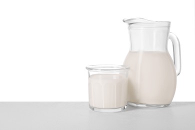 Glassware with tasty milk on light table against white background
