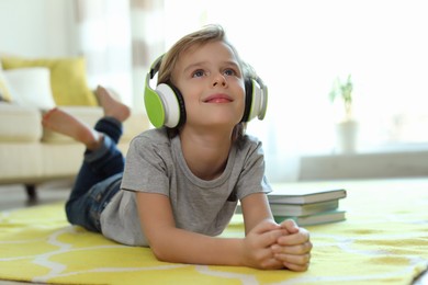 Cute little boy with headphones listening to audiobook at home