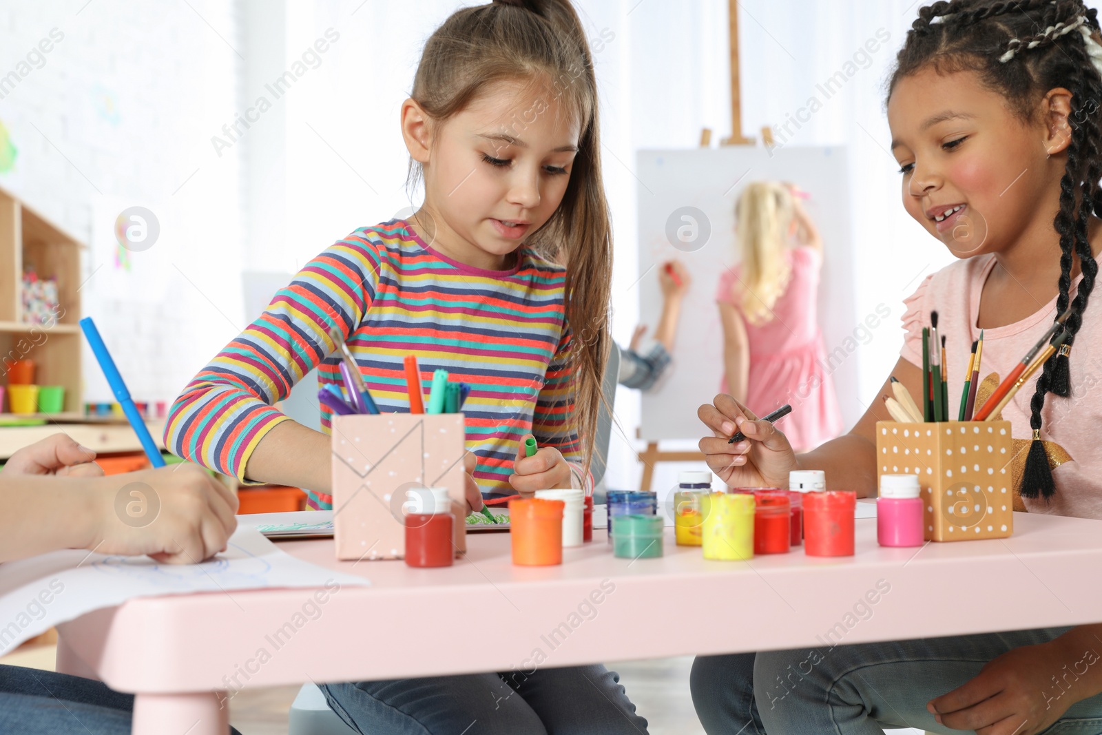 Photo of Cute little children drawing at painting lesson indoors