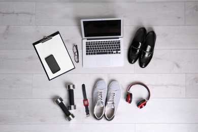 Flat lay composition of business items with sport accessories on white wooden background. Life and work balance concept