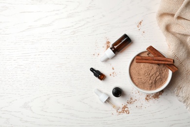 Photo of Bottles with cinnamon oil, powder and sticks on wooden background