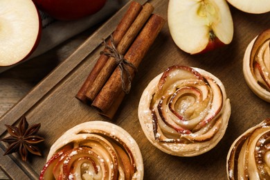 Photo of Freshly baked apple roses on wooden table, flat lay. Beautiful dessert