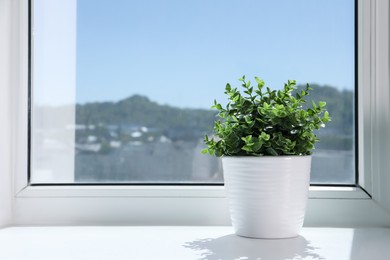Photo of Artificial potted herb on sunny day on windowsill indoors, space for text. Home decor
