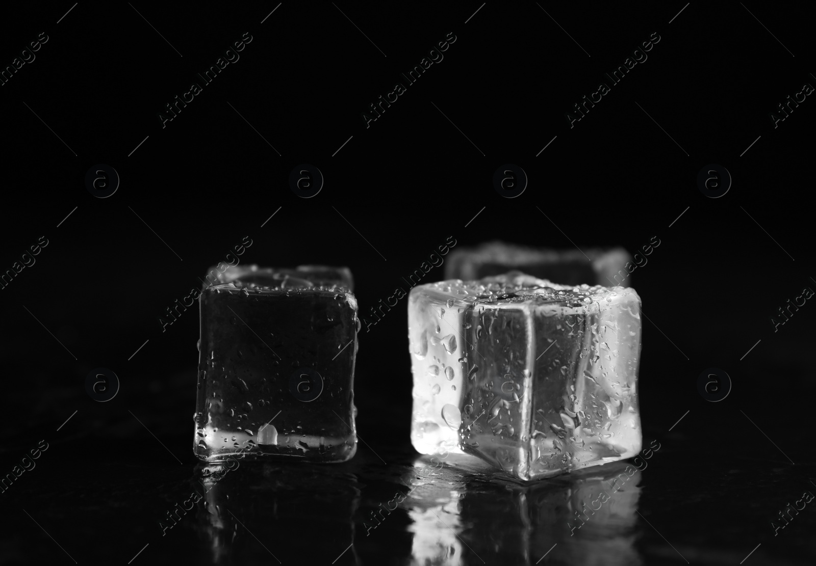 Photo of Ice cubes with water drops on black background, closeup