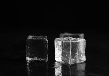 Photo of Ice cubes with water drops on black background, closeup