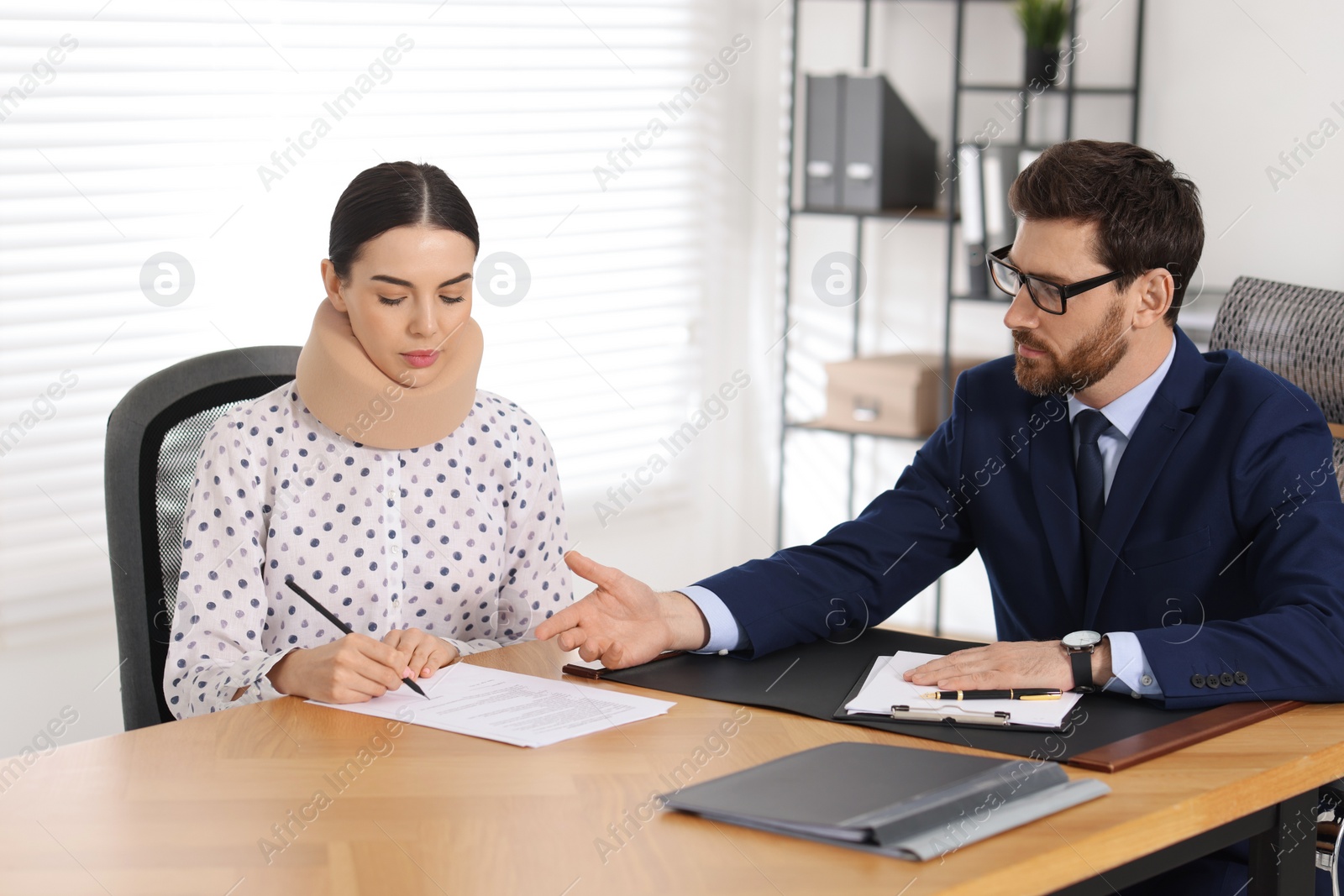 Photo of Injured woman signing document in lawyer's office