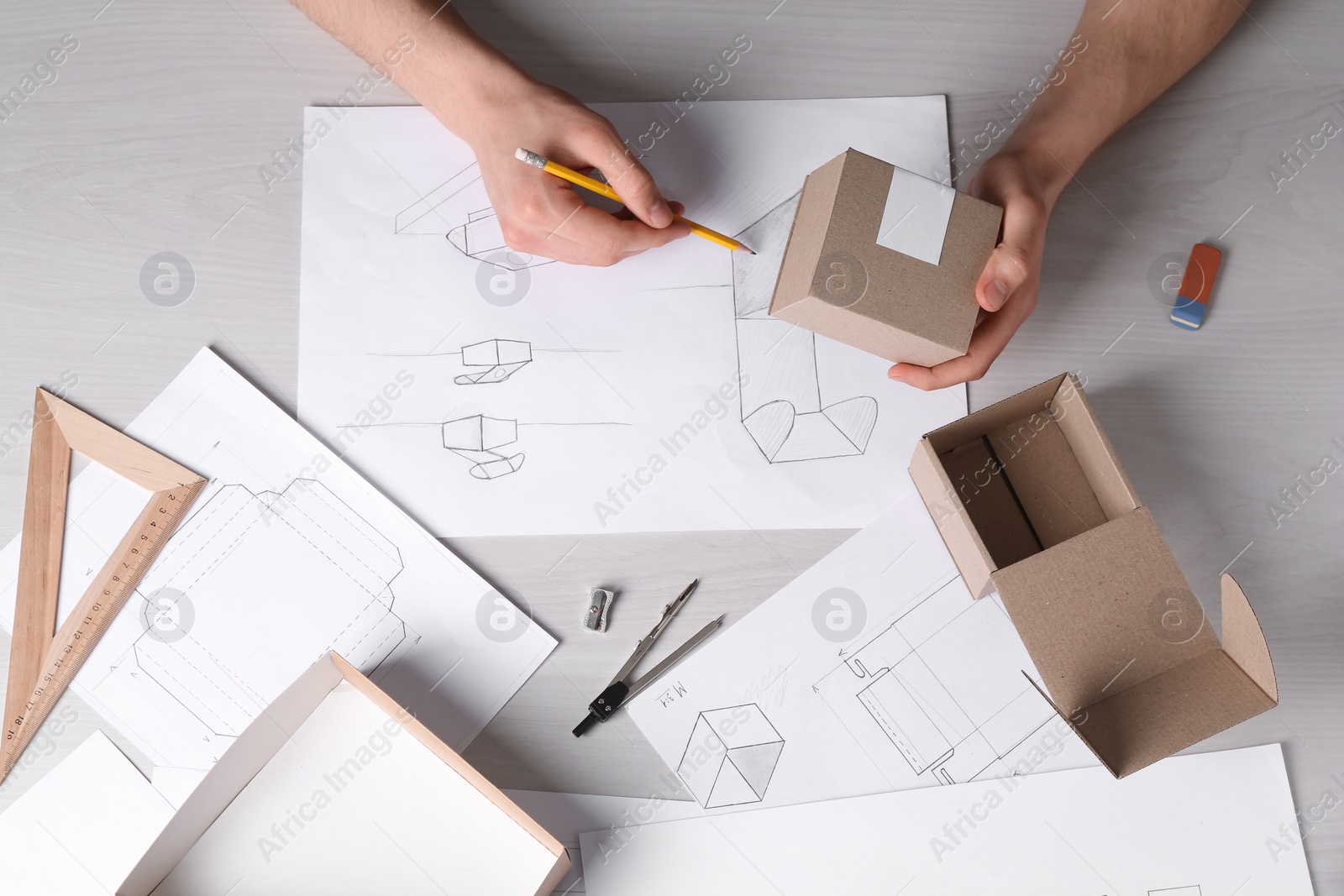 Photo of Man creating packaging design at light wooden table, top view