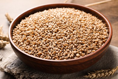 Photo of Wheat grains and spikes on wooden table, closeup