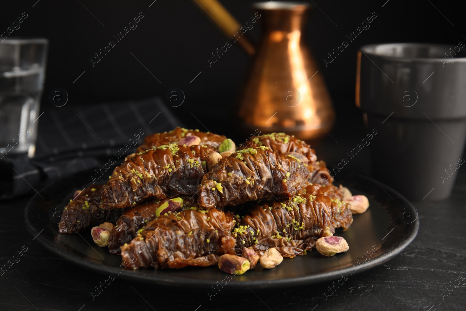 Photo of Delicious baklava with pistachio nuts on black table