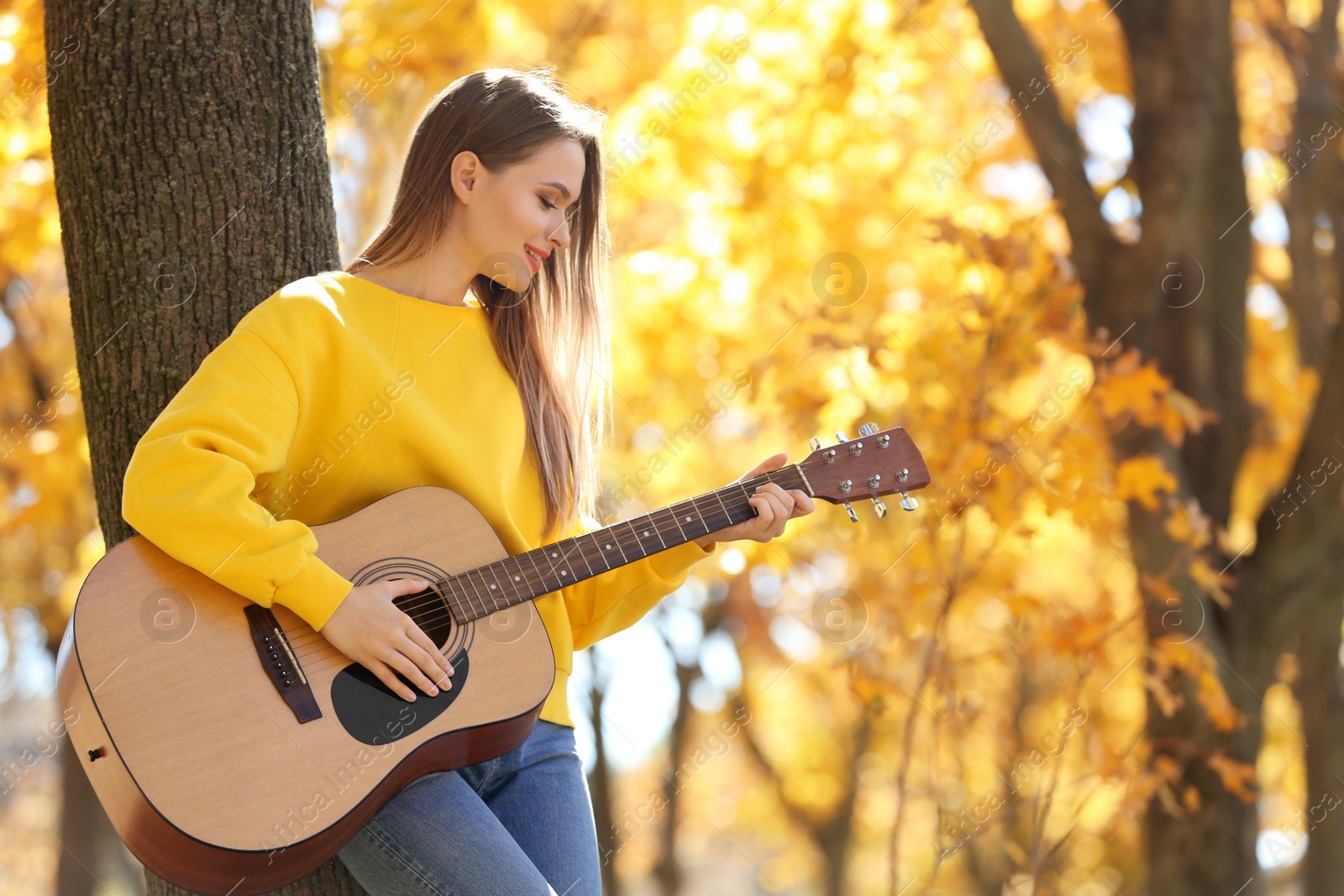 Photo of Teen girl playing guitar in autumn park