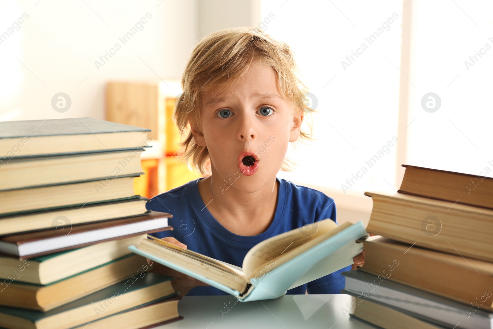 Photo of Emotional little boy doing homework at table indoors