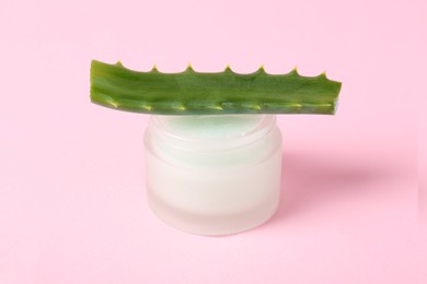 Photo of Jar of natural gel and cut aloe on pink background, closeup