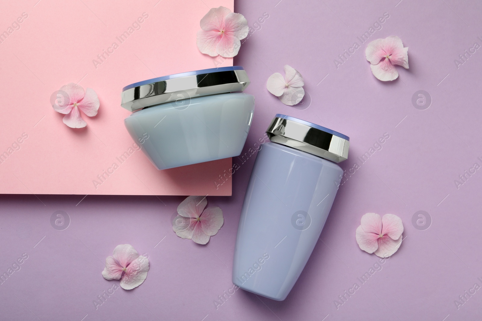 Photo of Hair care cosmetic products and petals on color background, flat lay
