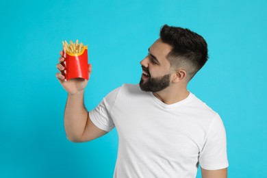 Photo of Young man with French fries on light blue background