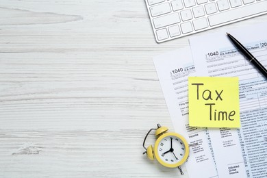 Photo of Reminder note with words Tax Time, documents, computer keyboard and alarm clock on white wooden table, flat lay. Space for text