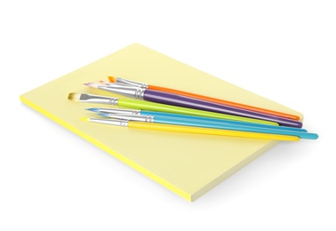 Photo of Notebook and different brushes on white background. School stationery