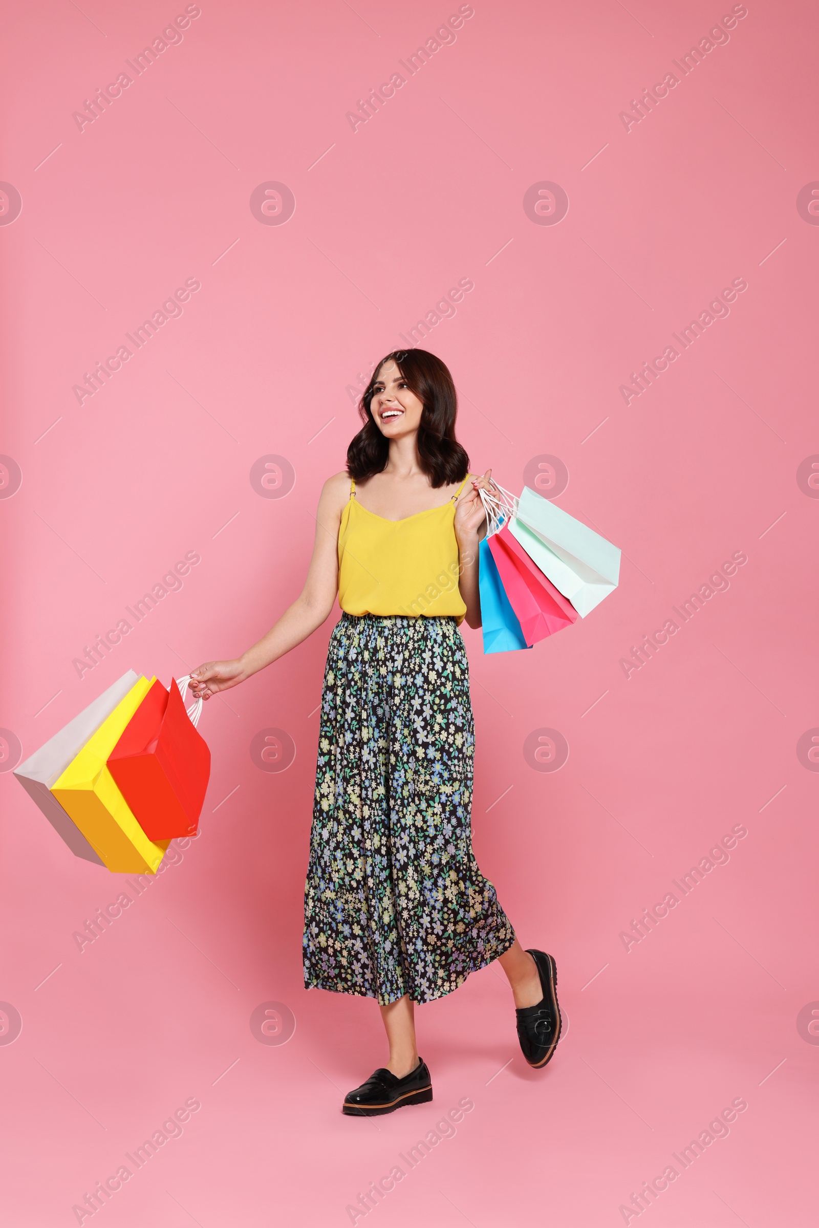 Photo of Beautiful young woman with paper shopping bags on pink background