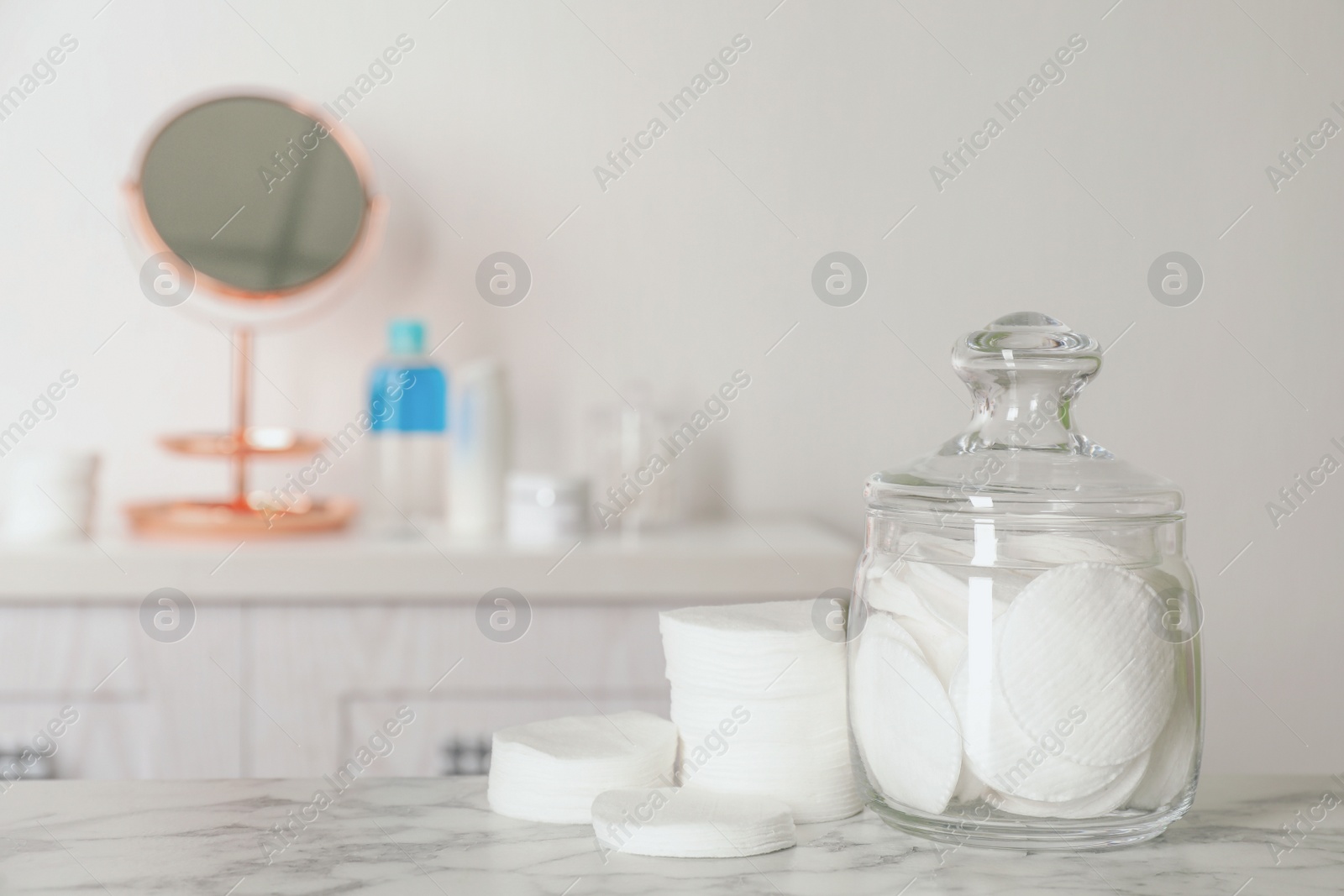 Photo of Glass jar with cotton pads for removing makeup on white marble table in bathroom