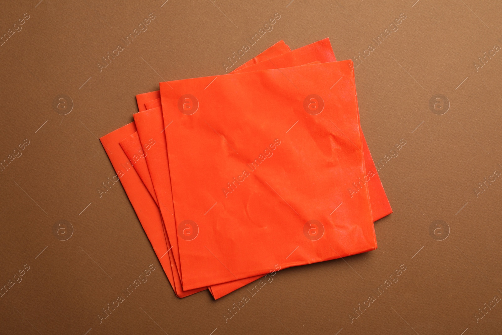 Photo of Red beeswax food wraps on brown background, top view